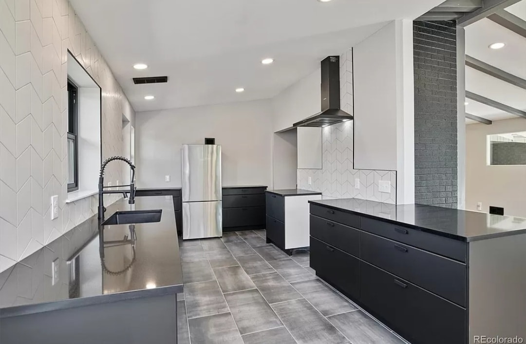 Matte black kitchen remodel by 303 Construction — flat-front cabinets, dark quartz countertops, chevron tile backsplash